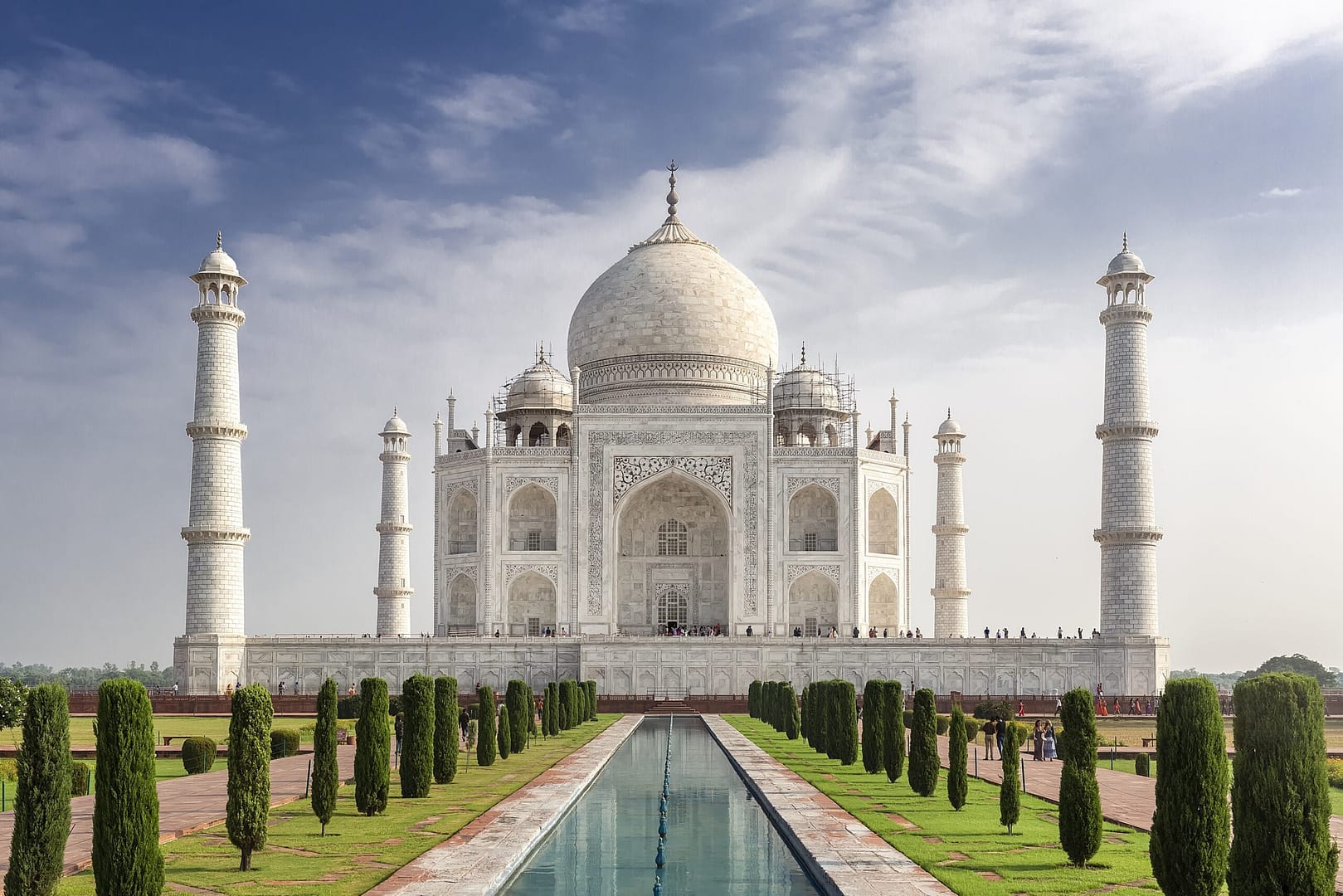 Ivory-white marble Taj Mahal glowing in the sunlight, surrounded by lush gardens.